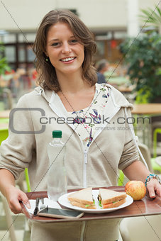 Female student carrying food tray in the cafeteria
