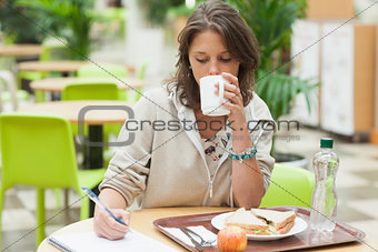 Student doing homework and having breakfast in cafeteria