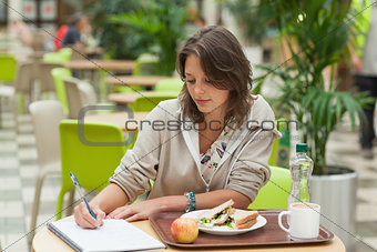 Student doing homework while having breakfast in the cafe