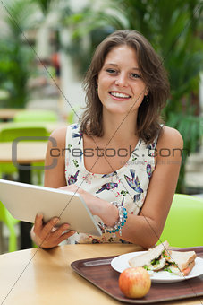 Woman with tablet PC and meal in the cafeteria