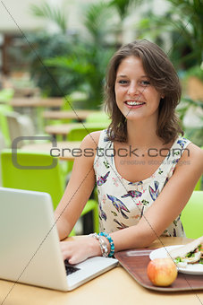 Woman with laptop and meal in the cafeteria