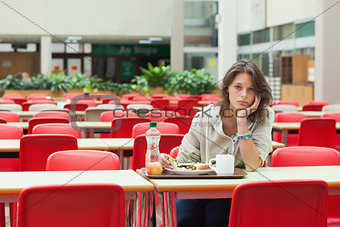 Sad student sitting in the cafeteria with food tray