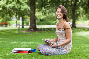Female student sitting with books at the park