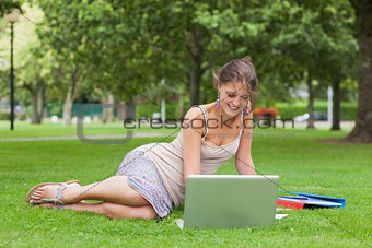 Student with laptop and books at the park