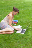 Female student with laptop and books at the park