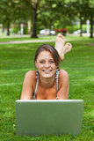 Woman lying on grass and using laptop