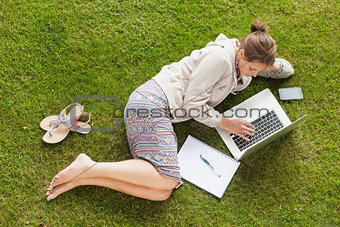 Female student using laptop with books at the park