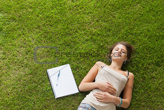 Female student resting on grass at the park