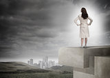 Businesswoman in front of cloudy sky and landscape with buildings