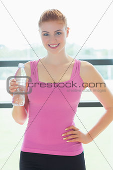 Woman with water bottle standing in fitness studio