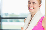Smiling woman with towel around neck listening to music in fitness studio