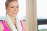 Woman with towel around neck listening to music in fitness studio