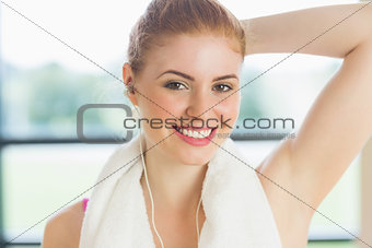 Woman with towel around neck listening to music in fitness studio