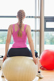 Rear view of a fit woman sitting on exercise ball