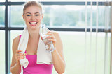 Cheerful woman with towel around neck holding water bottle