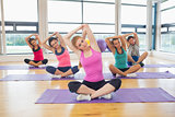 Portrait of fitness class and instructor stretching hands on yoga mats