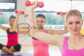 Fitness class and trainer lifting dumbbells