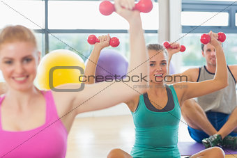 Fitness class and trainer lifting dumbbells