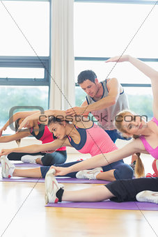 Trainer helping woman at fitness studio