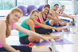 Portrait of fitness class and instructor stretching legs