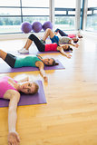 Class lying on exercise mats in row at fitness studio