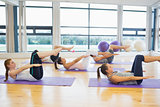 Class stretching on mats at yoga class in fitness studio