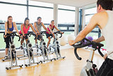 Man teaching spinning class to four people