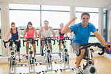 Happy man teaches spinning class to four people
