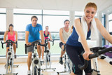 Happy woman teaches spinning class to four people