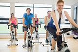Happy woman teaches spinning class to four people