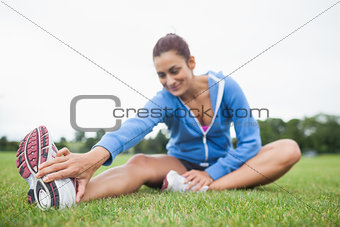 Woman stretching her leg while sitting on the grass