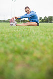 Sporty woman stretching her legs while sitting on grass
