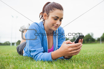Pretty woman with mobile phone lying on grass