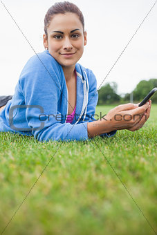 Pretty woman with mobile phone lying on grass