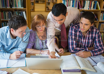Mature students with teacher and laptop in library