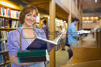 Smiling mature student with men in the background at library