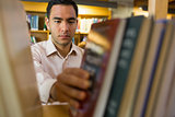 Mature student selecting book from shelf in the library