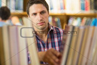 Mature student selecting book from shelf in library
