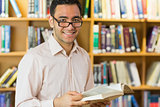 Smiling mature student reading book in library