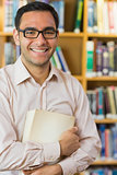 Smiling mature student against bookshelf in library