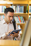 Concentrated mature student using tablet PC in library