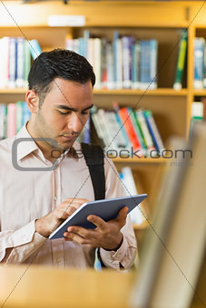 Concentrated mature student using tablet PC in library