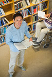 Man by disabled student in wheelchair in the library