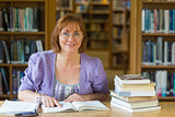 Smiling mature female student at desk in the library