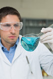 Male researcher  looking at flask with blue liquid in the lab