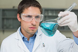 Male researcher  looking at flask with blue liquid in the lab