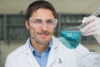 Male researcher  holding flask with blue liquid in the lab
