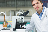 Smiling scientific researcher with microscope in laboratory