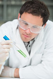 Scientist analyzing green solution in test tube at the lab