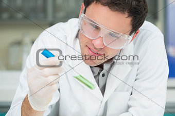 Scientist analyzing green solution in test tube at the lab